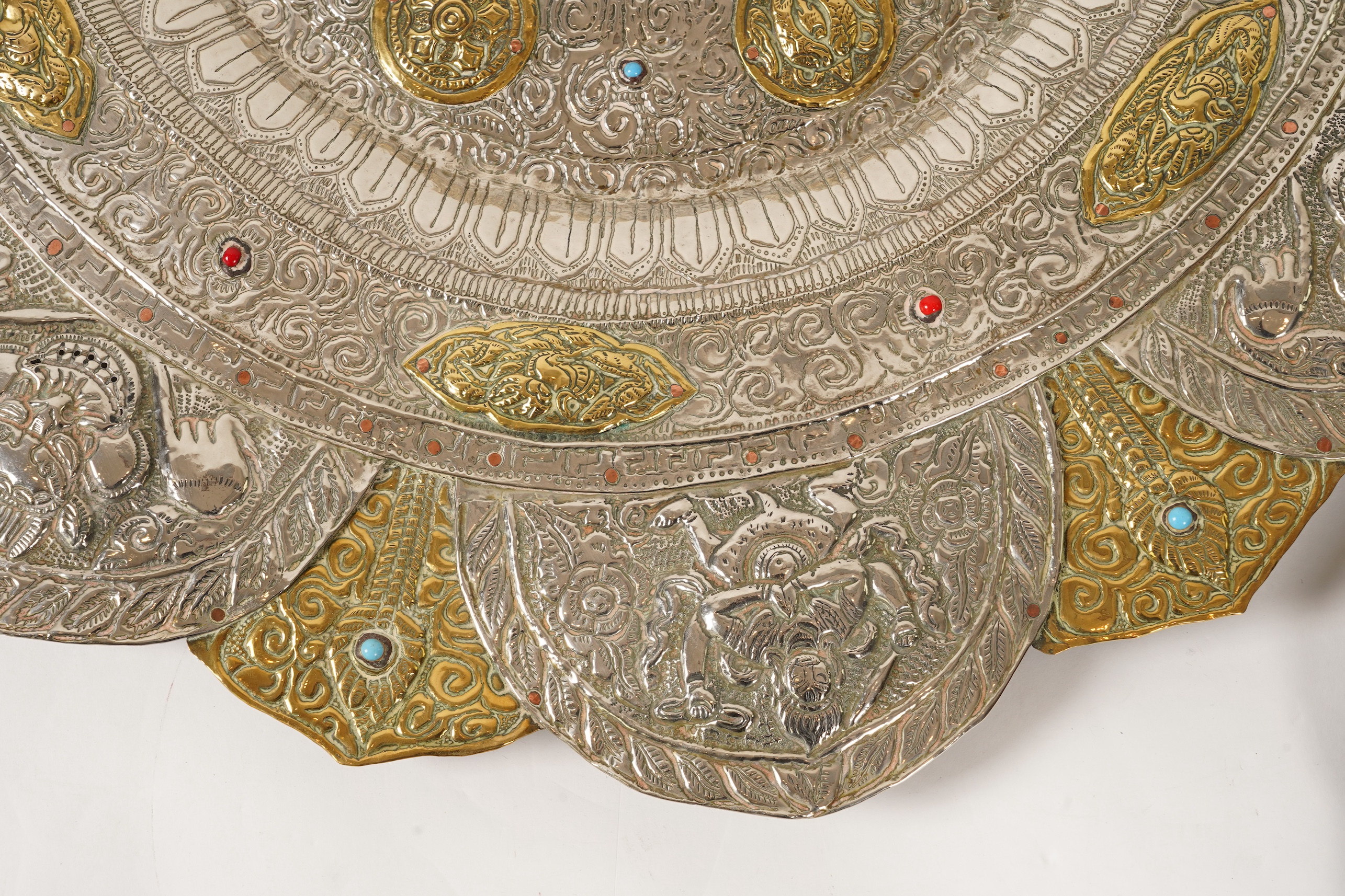 A graduated set of three Nepalese repoussé white metal and brass chargers, first half 20th century